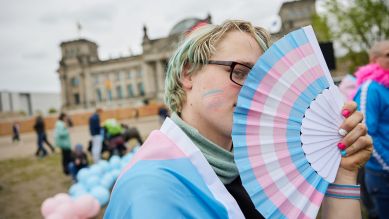 Amity steht bei einer Protestveranstaltung gegen das Selbstbestimmungsgesetz von Frauengruppen mit einem Fächer in den Transgender-Farben vor dem Bundestag, Foto: dpa/Jörg Carstensen