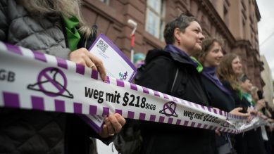 Aktivistinnen halten ein Band mit einem durchgestrichenen Kleiderbügel und dem Schriftzug "weg mit dem §218 StGB", Foto: dpa/Sebastian Gollnow